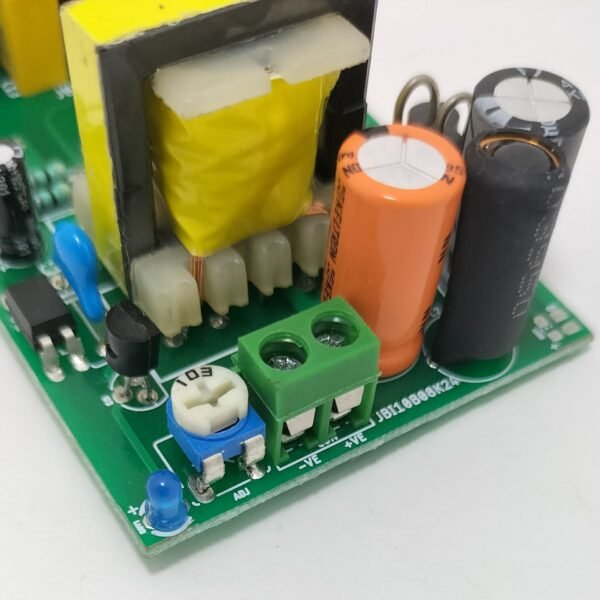 SMPS PCB terminal block close up with regulated DC output connection and filtering capacitors