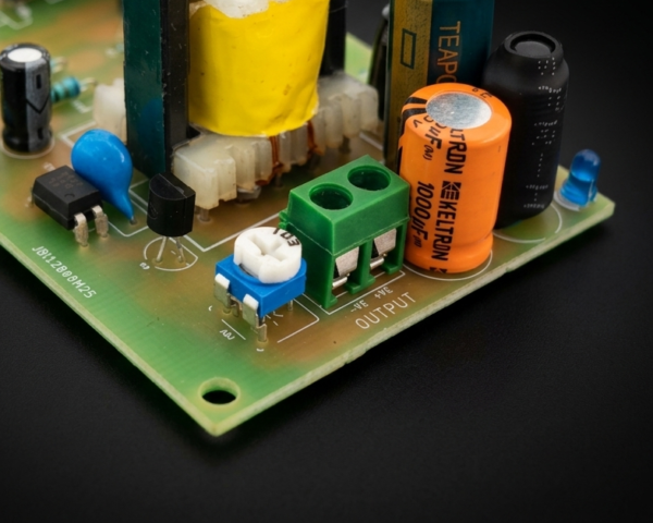 SMPS PCB terminal block close up with regulated DC output connection and filtering capacitors